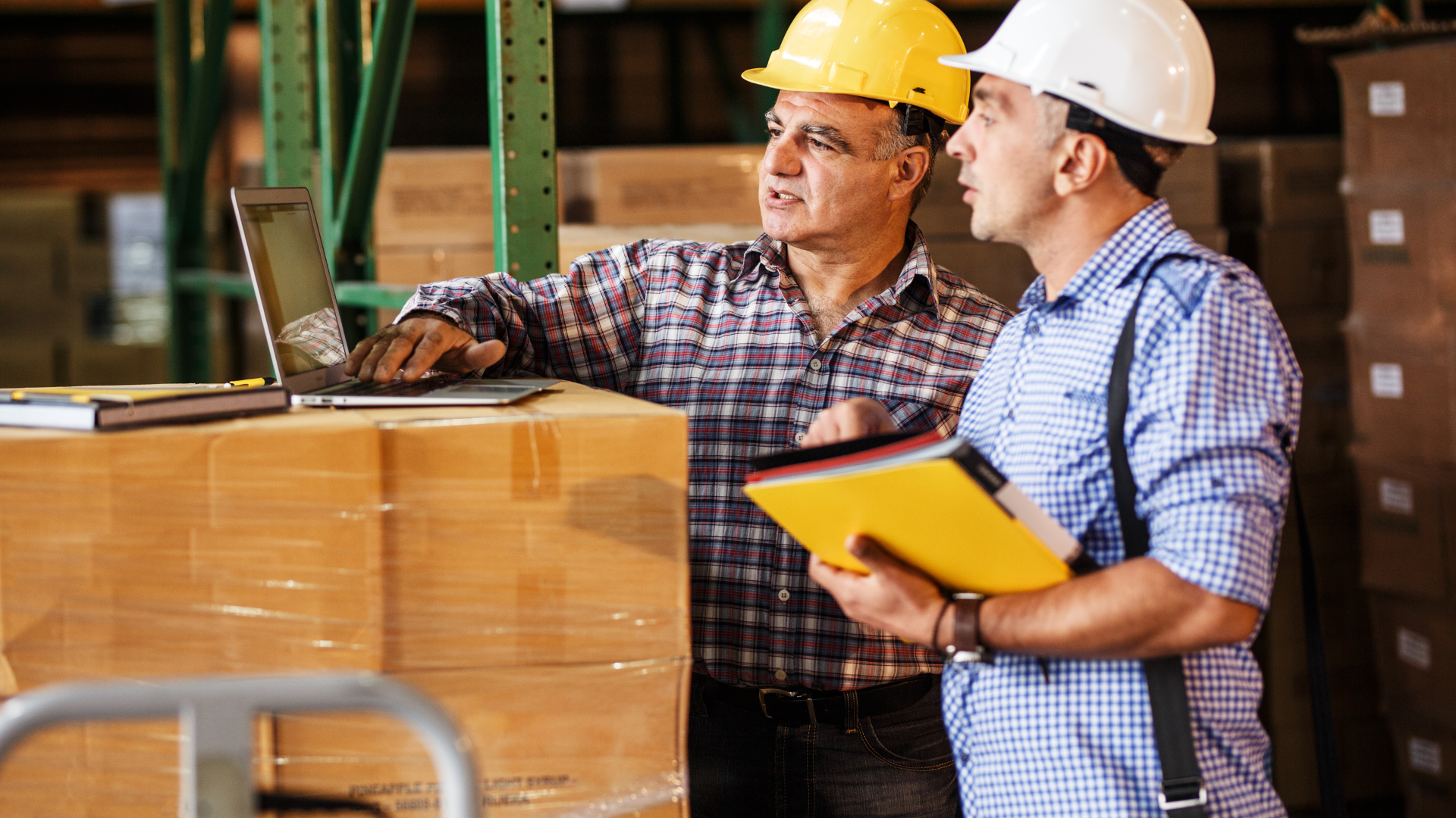 two male contractors looking over plans on a laptop