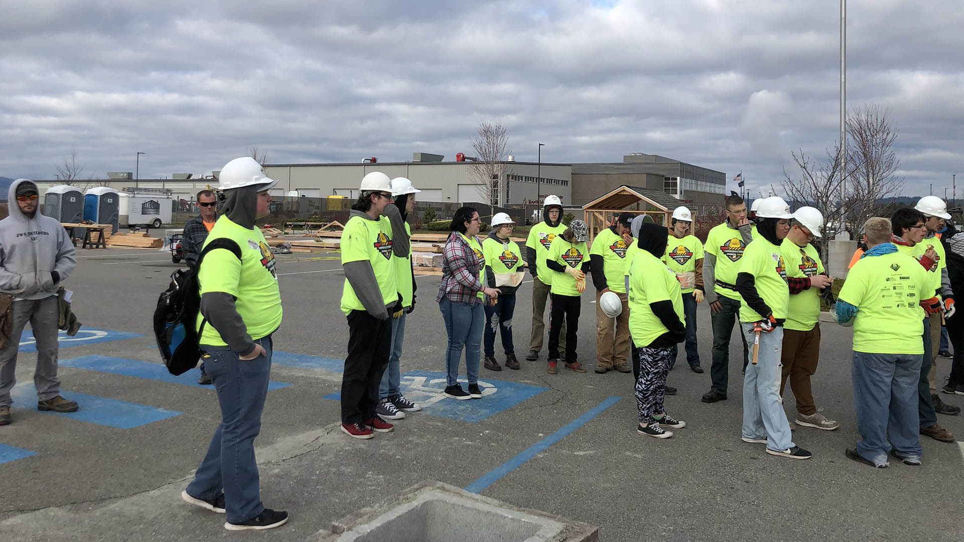 A group of young people in construction combine shirts and hardhats learning about construction