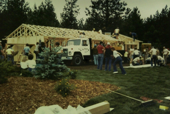 old photograph of the one day house event, truck in front of the unfinished, framed house